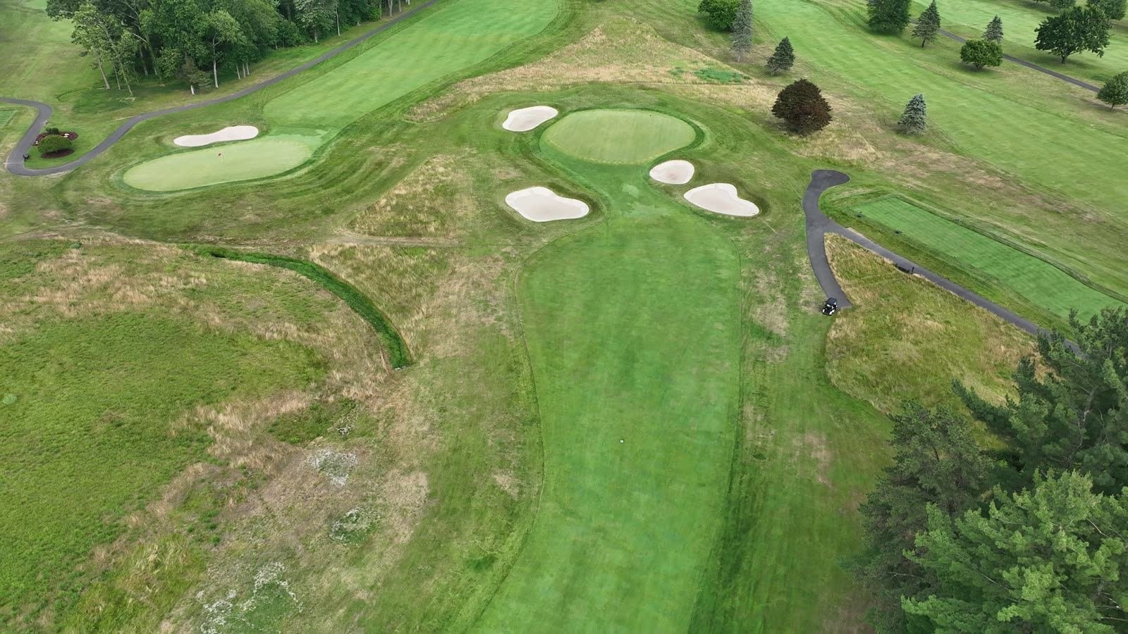 Overhead aerial of a green complex and surrounding bunkers